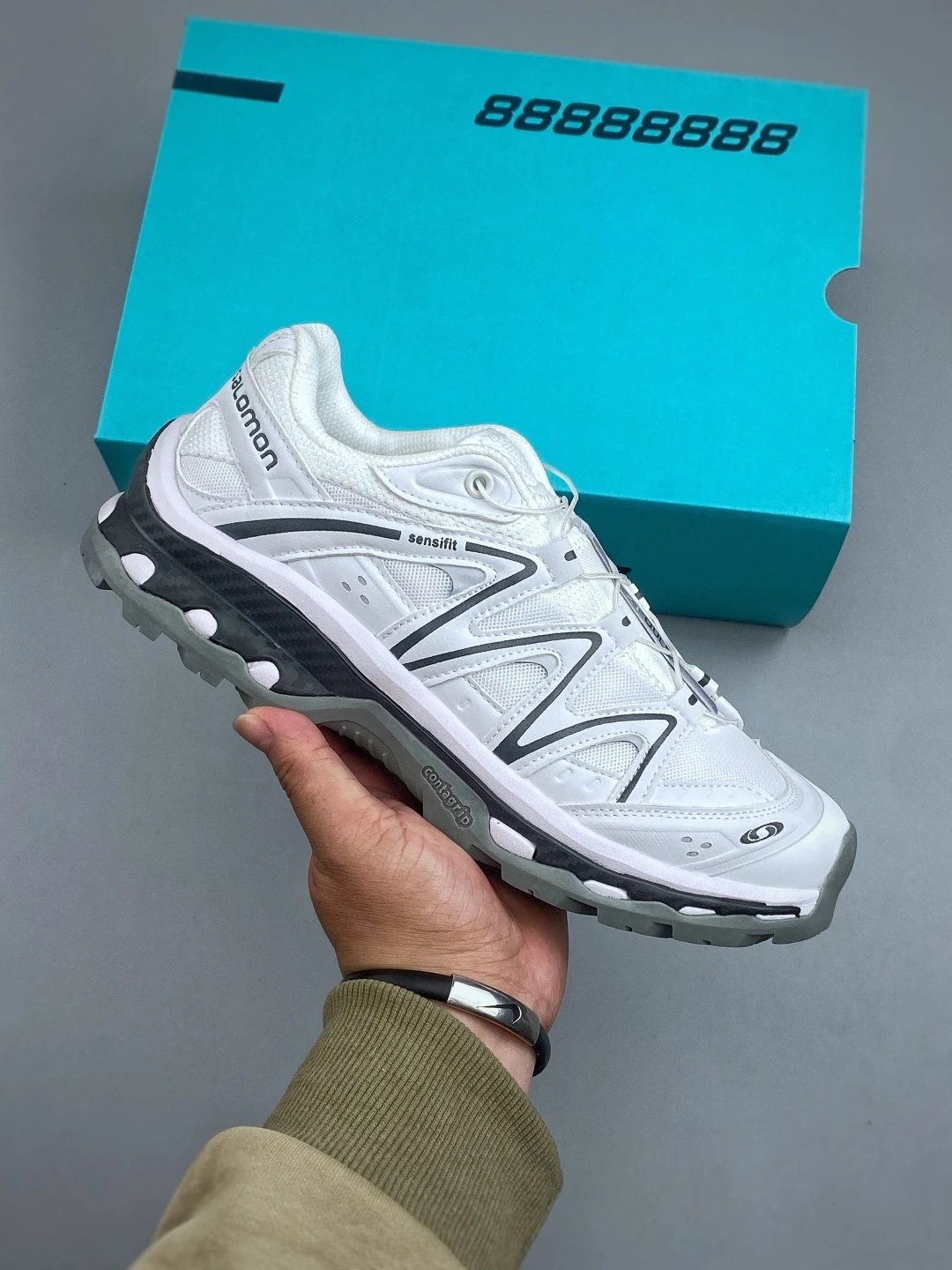 Salomon White and Gray Trail Runners Highlighting Treaded Trail Sole